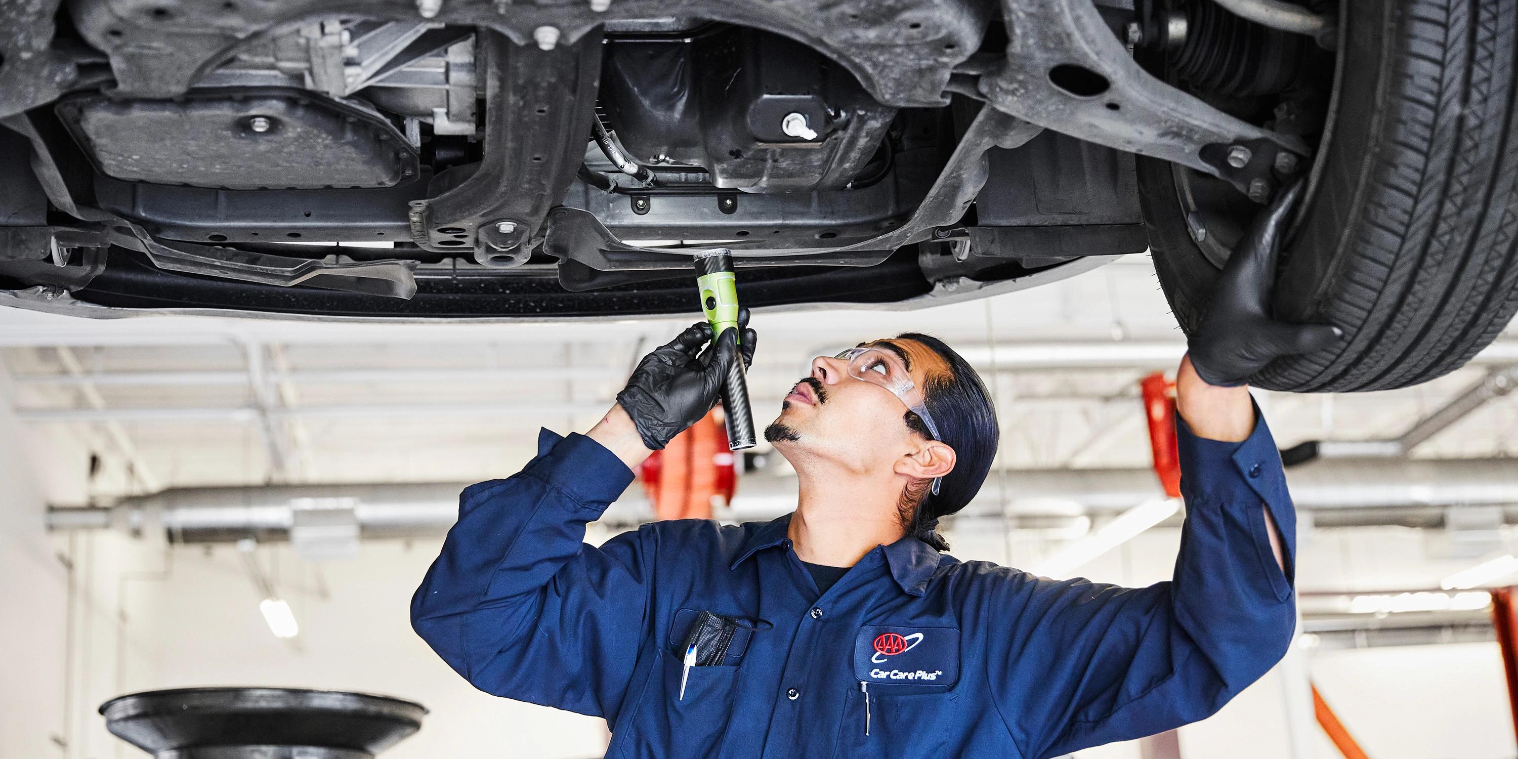 Another man inspecting the underside of a car