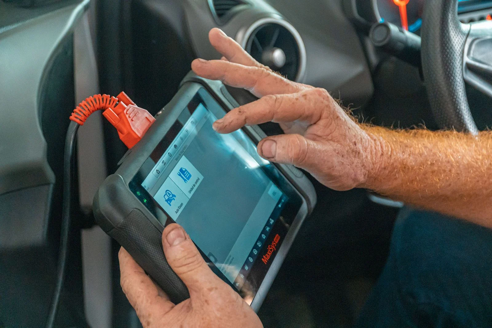 An automotive technician diagnosing a vehicle with a diagnostic tool