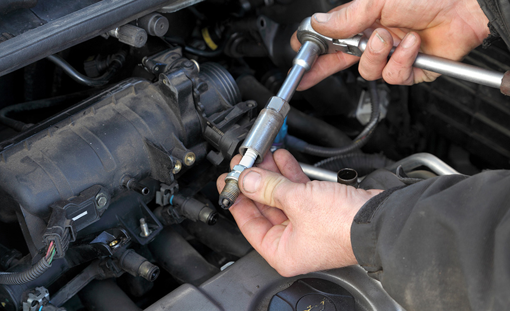 An automotive techician inspecting an engine's spark plugs