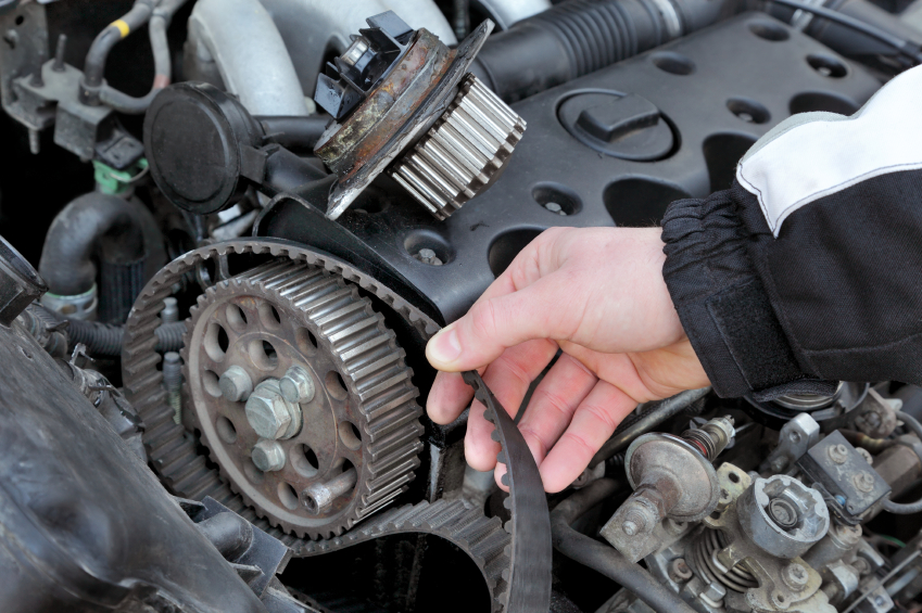 An automotive technician holding onto a loose timing belt
