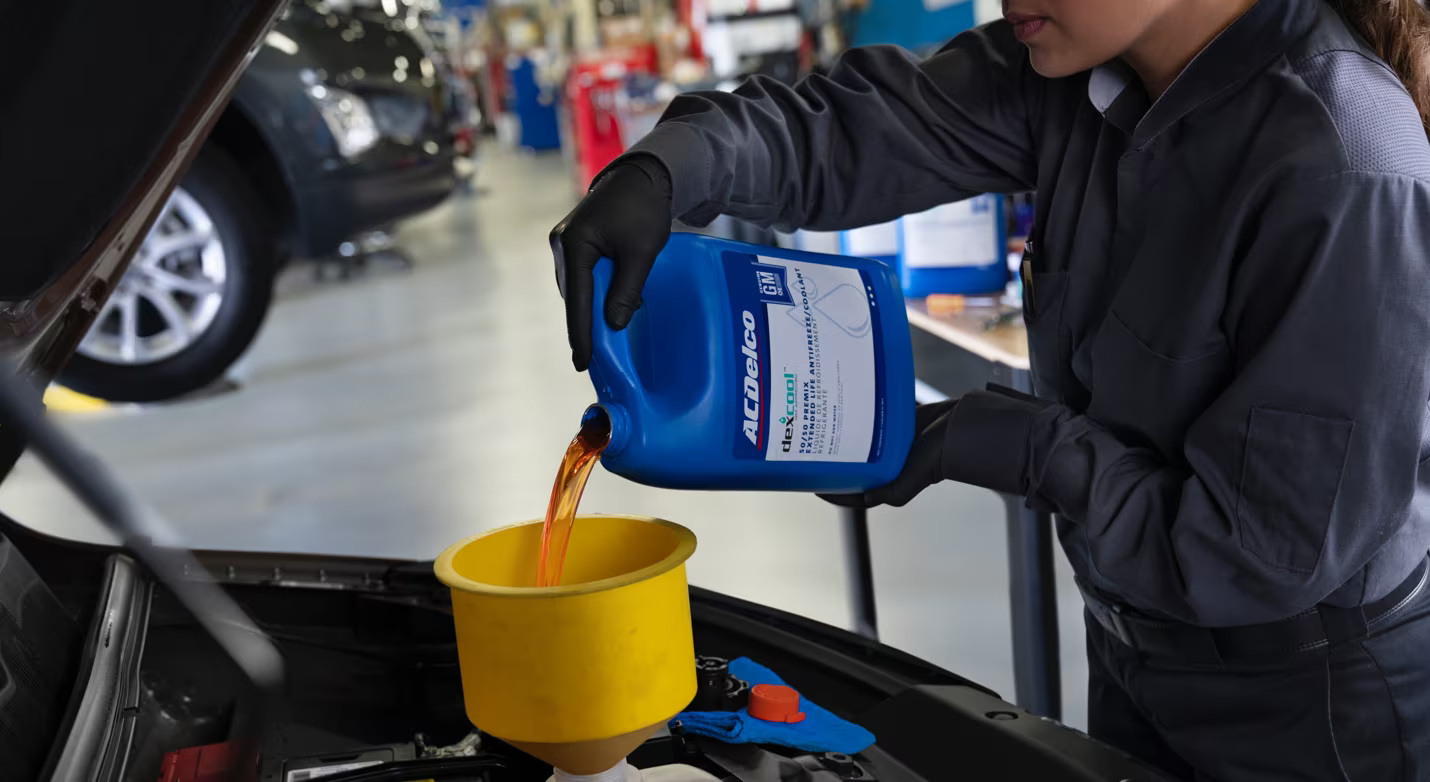 An automotive technician refilling oil with a funnel