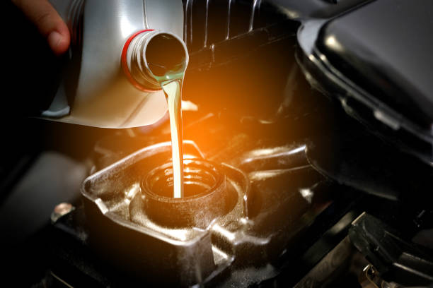 An automotive technician pouring oil into a vehicle