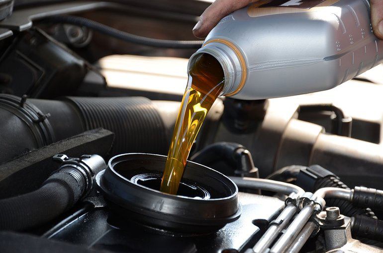 An automotive technician pouring oil into a vehicle