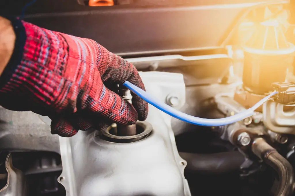 An automotive technician with a glove on fixing an oxygen sensor