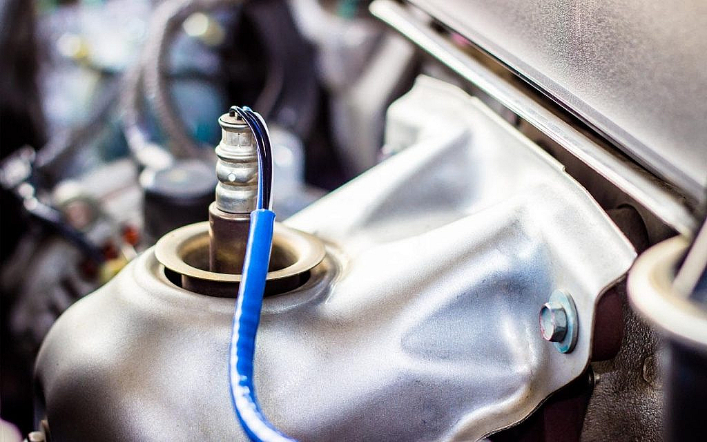 A closeup of an installed oxygen sensor with a blue wire