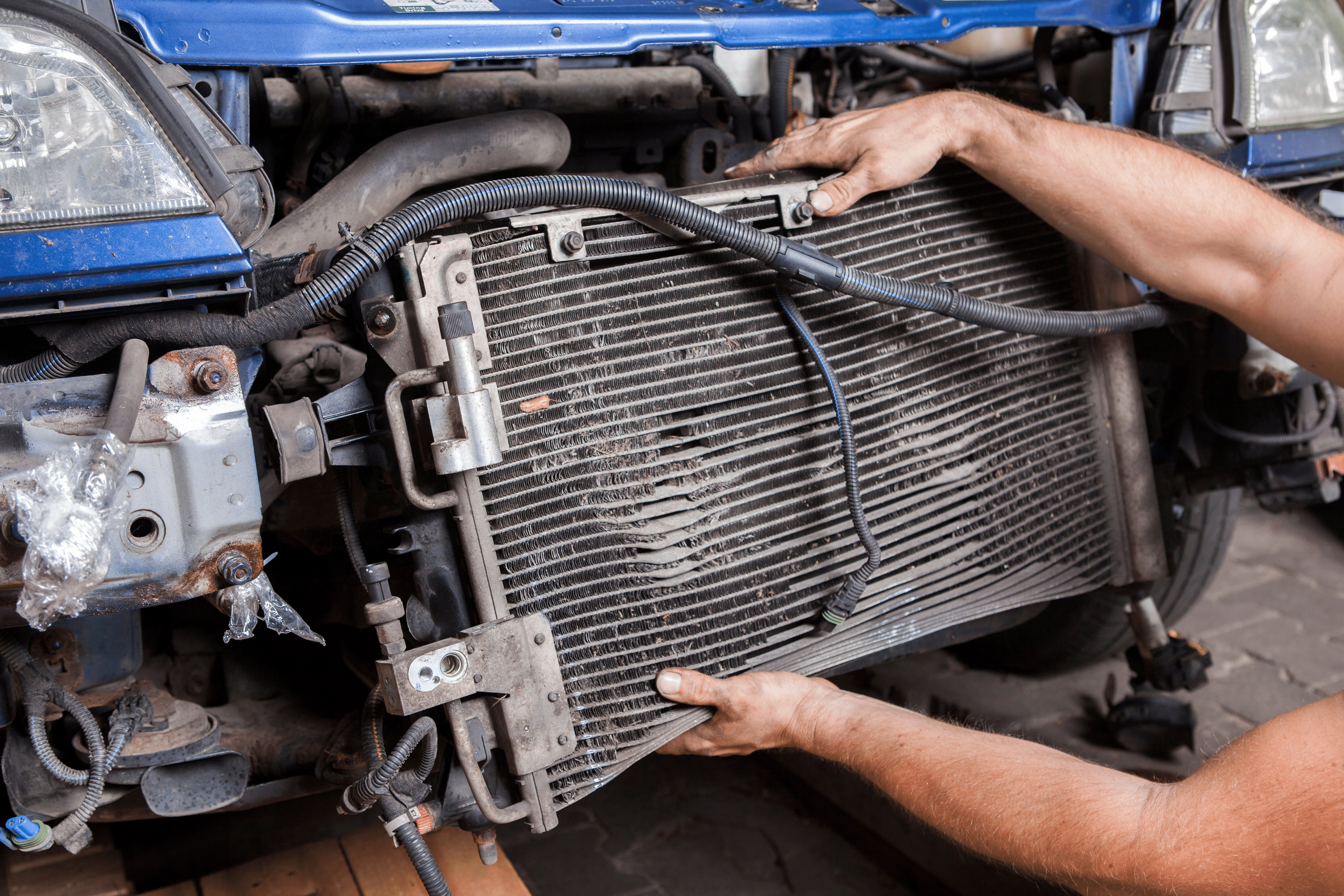 An automotive technician installing a new radiator