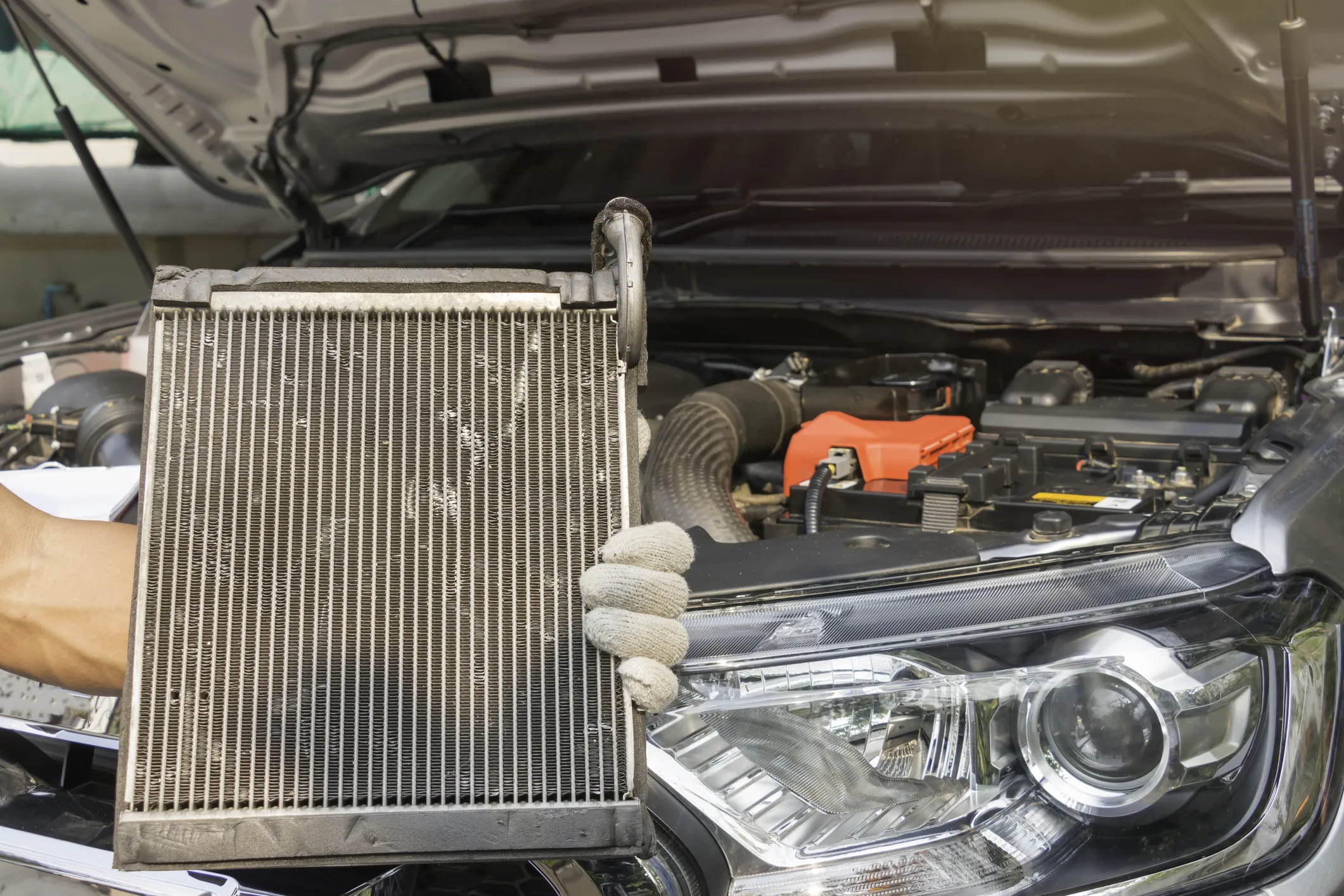An automotive technician holding a radiator up to the camera