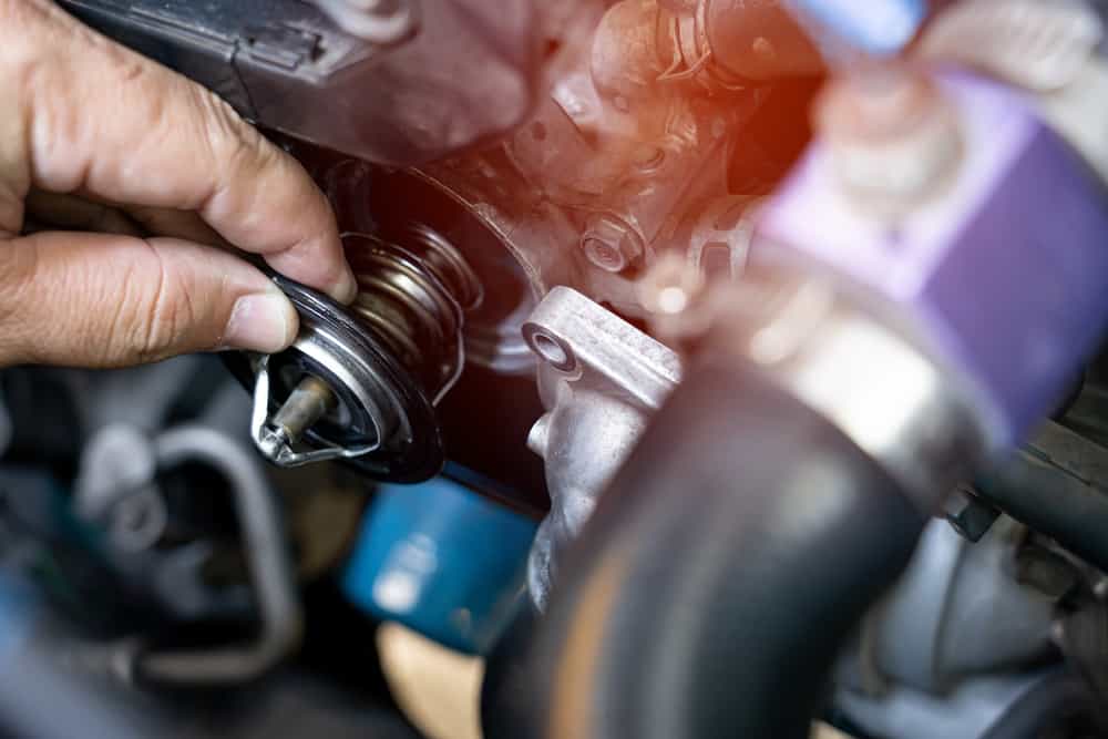 An automotive technician replacing a thermostat