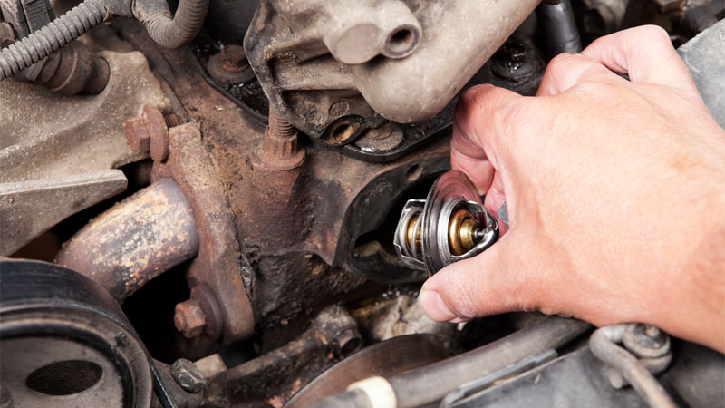 An automotive technician removing a thermostat