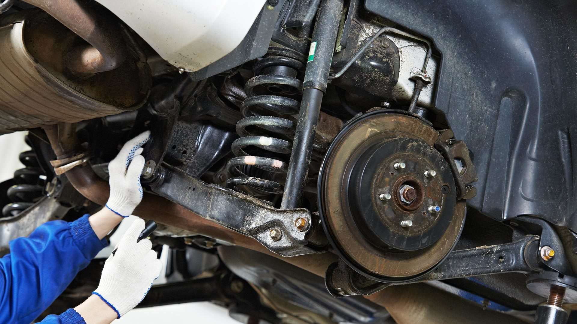 Another automotive technician inspecting a vehicle's suspension system