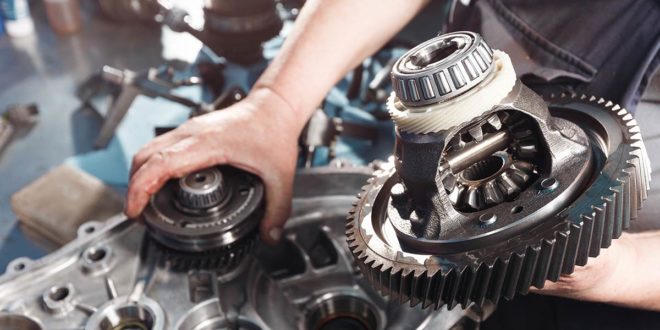 An automotive technician holding the gears of a transmission