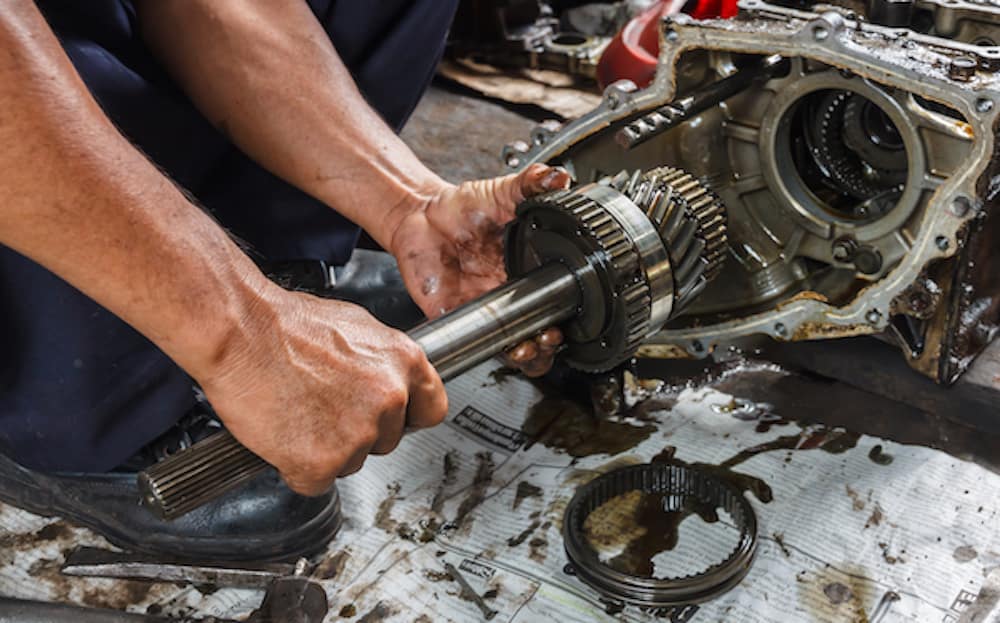 An experienced automotive technician repairing a transmission