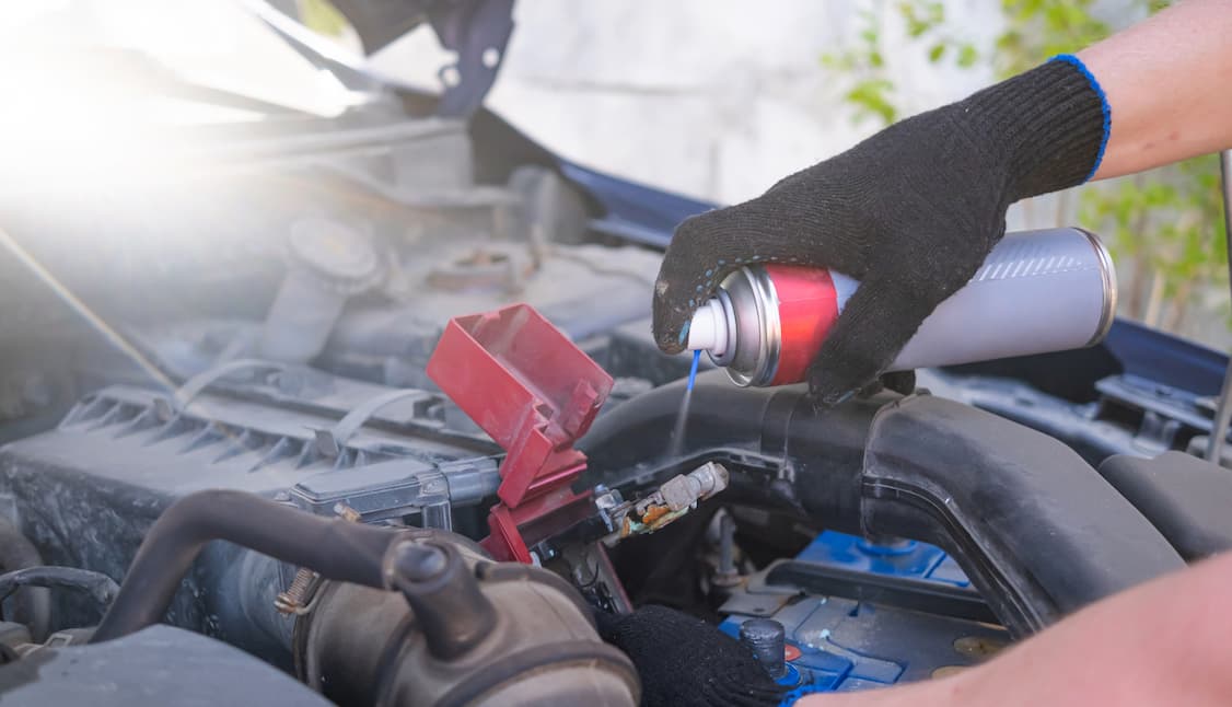 An automotive technician cleaning battery terminals