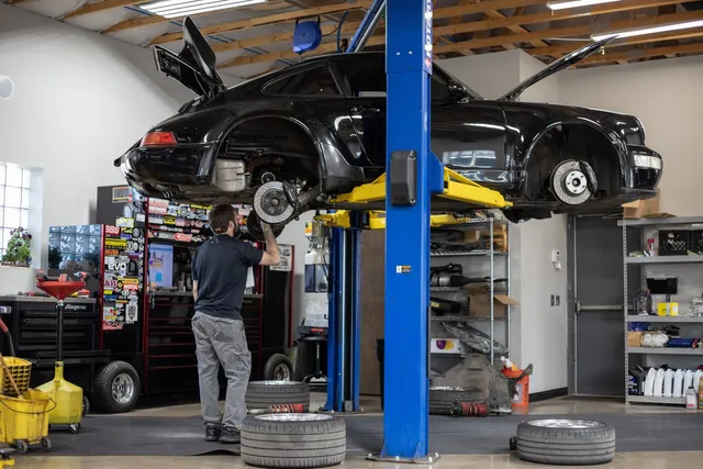 A vehicle on the lift with an automotive technician inspecting from underneath