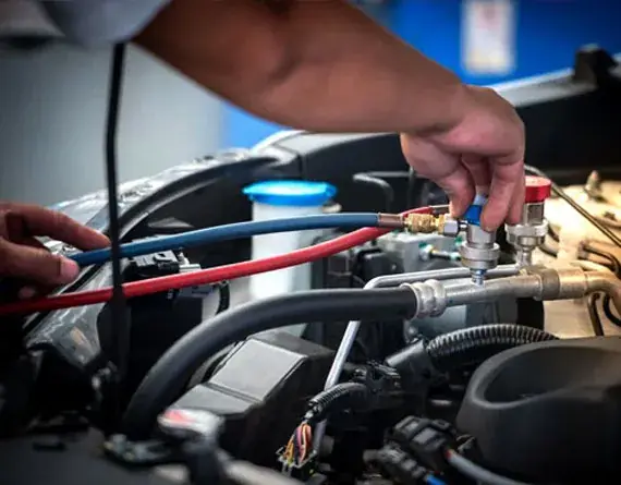 Mechanic connecting AC refrigerant hoses to a vehicle engine at Beach Auto & Transmission Repair in Virginia Beach